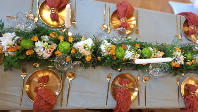 Elegant gedeckter Tisch mit goldenen Tellern und Blumen-Läufer