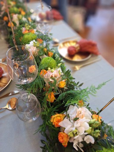 Tischdeko mit Blumen und Gläsern, vorbereitet für eine festliche Mahlzeit.